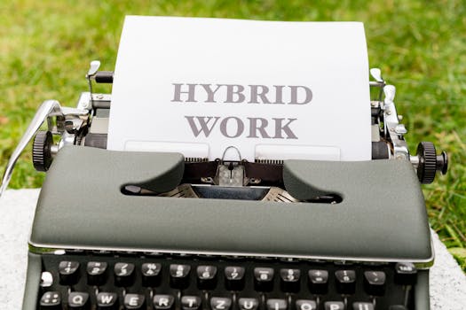 A vintage typewriter with a sheet displaying the text 'Hybrid Work' outdoors on grass.