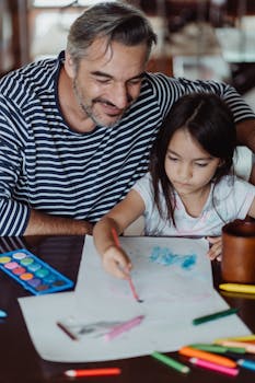 Father and daughter share a creative moment painting together at home.