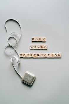 Inspiring fitness concept with 'Body Under Construction' in Scrabble tiles and a tape measure.